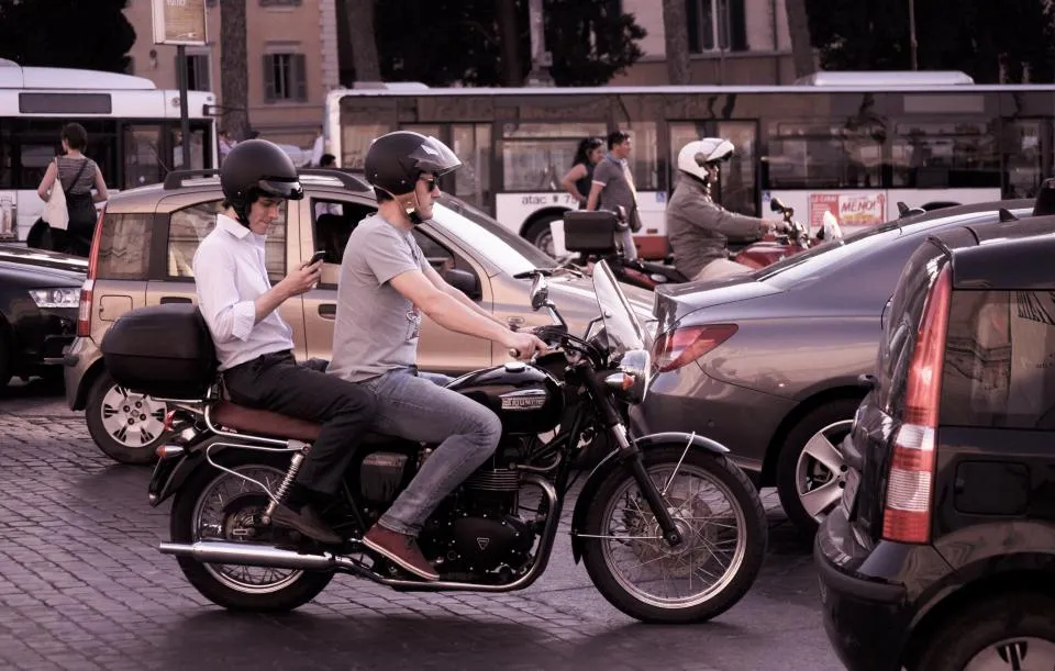 Two riders on a motorbike waiting in city traffic